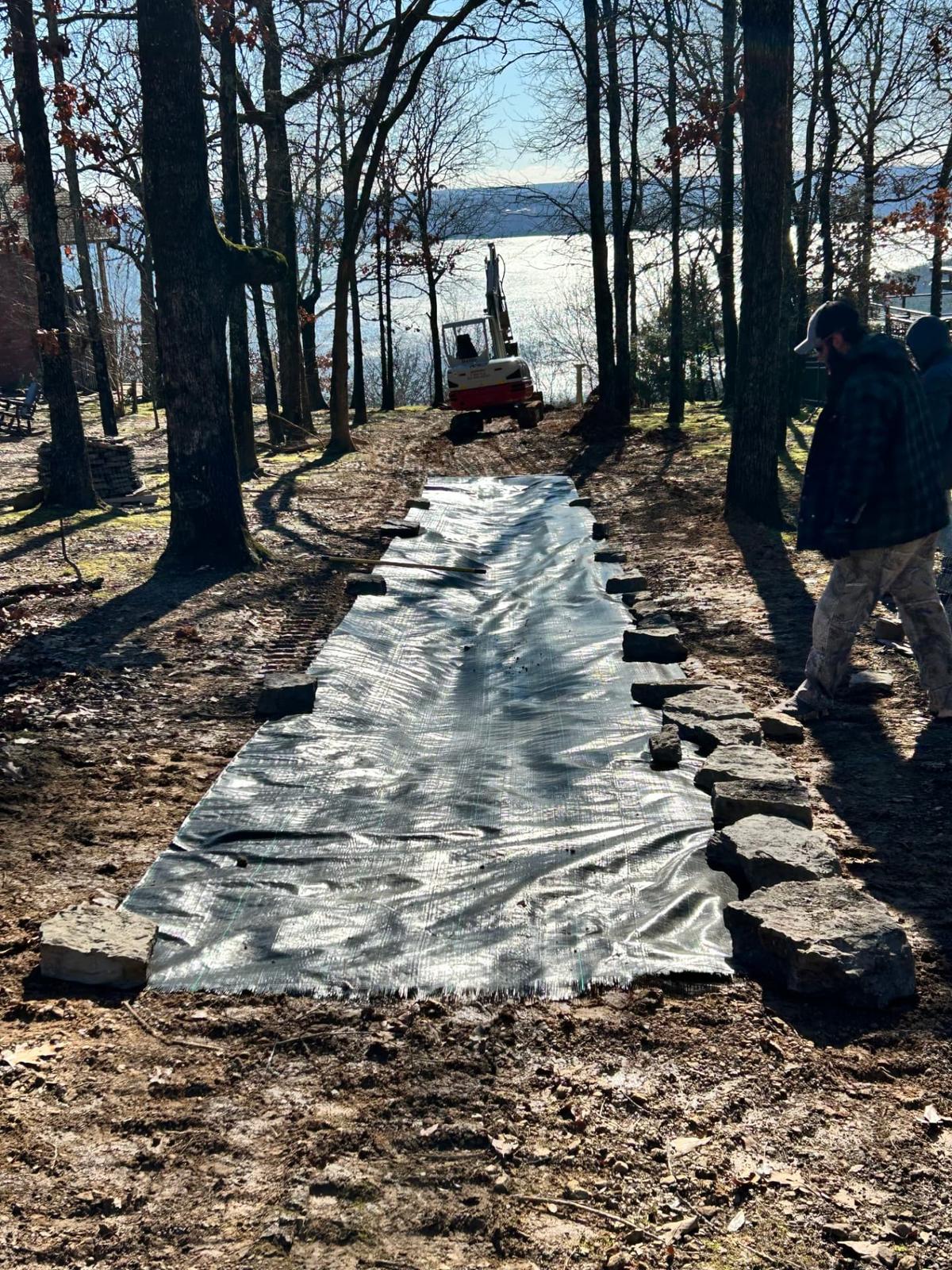 Filter fabric laid in a graded trench with a mini excavator before stone drainage work near Greers Ferry Lake