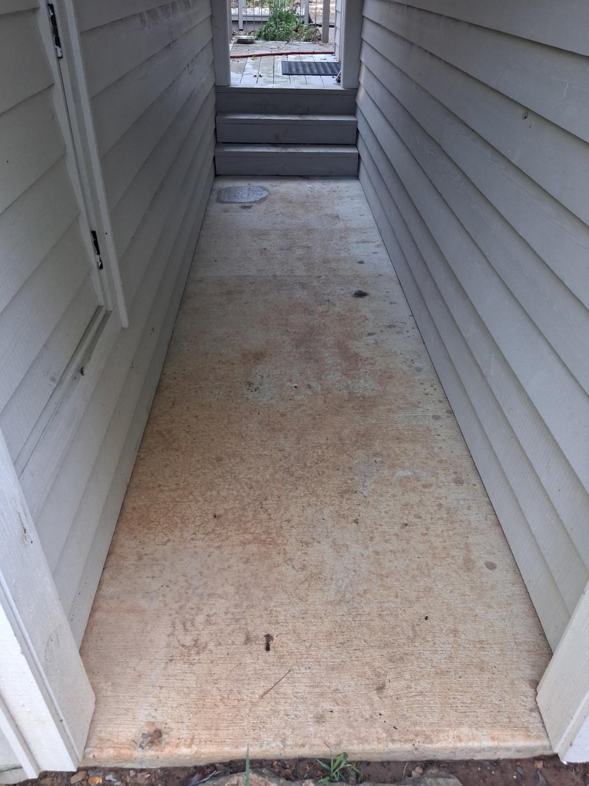 Narrow stained concrete walkway between two house walls before flagstone installation in Greers Ferry, Arkansas