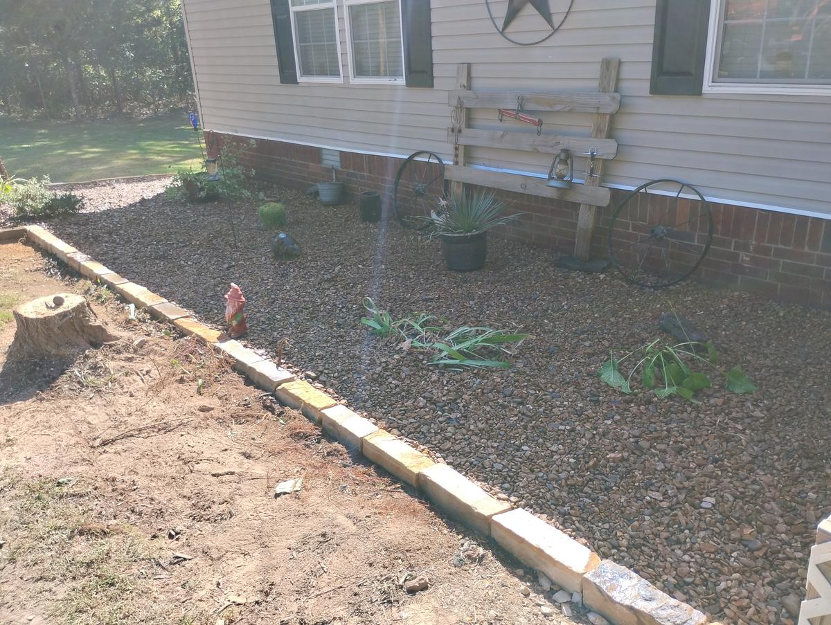 Finished river gravel flower bed with new stone block edging along a house in Greers Ferry, Arkansas