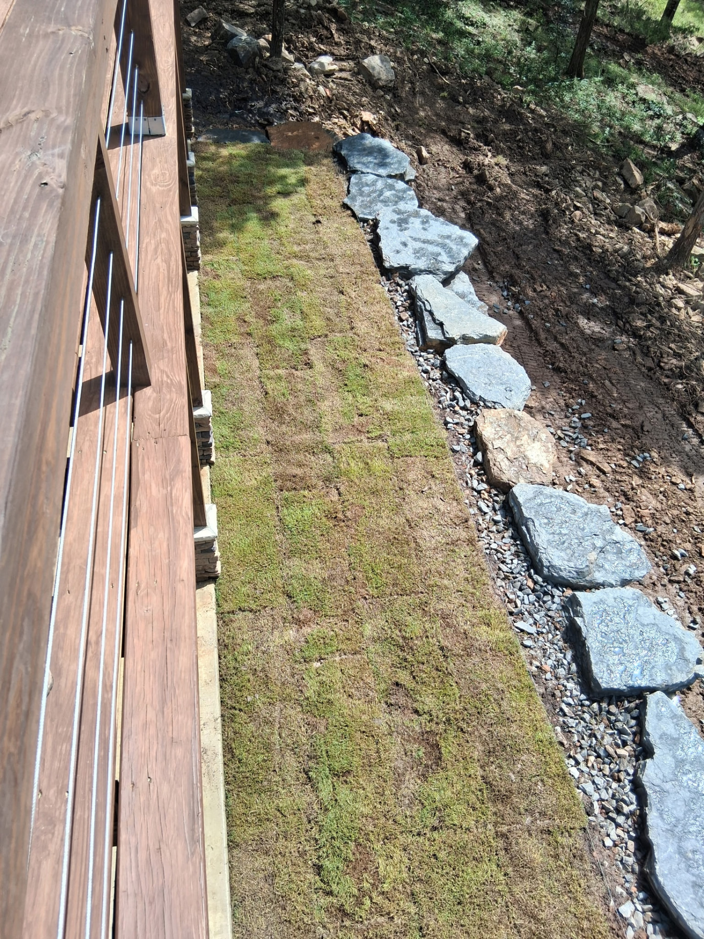 Fresh sod strip laid tight against a boulder border and gravel walk.