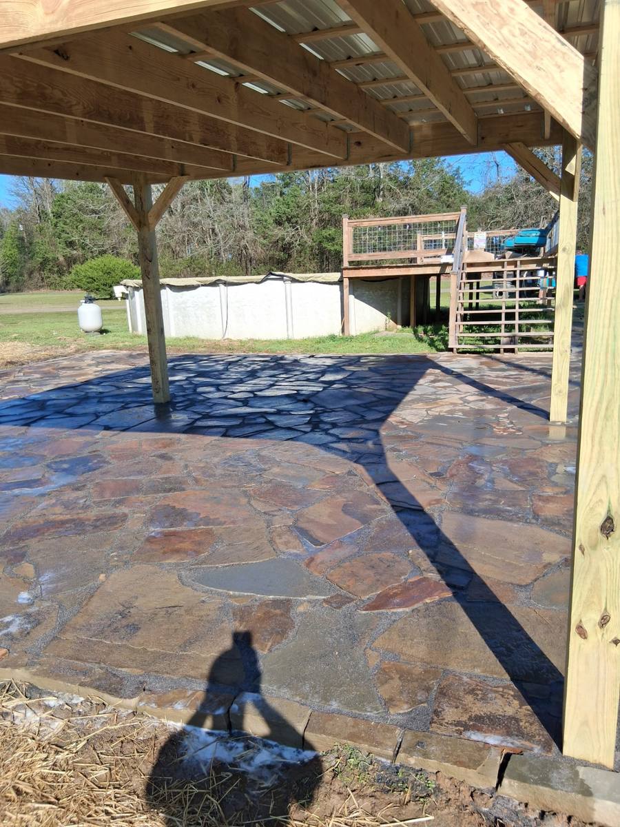 Mortared flagstone floor under a new metal-roof pavilion by the pool.