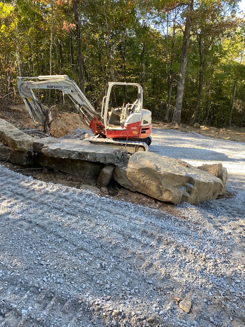 Mini-ex work setting boulders and shaping a drainage edge.