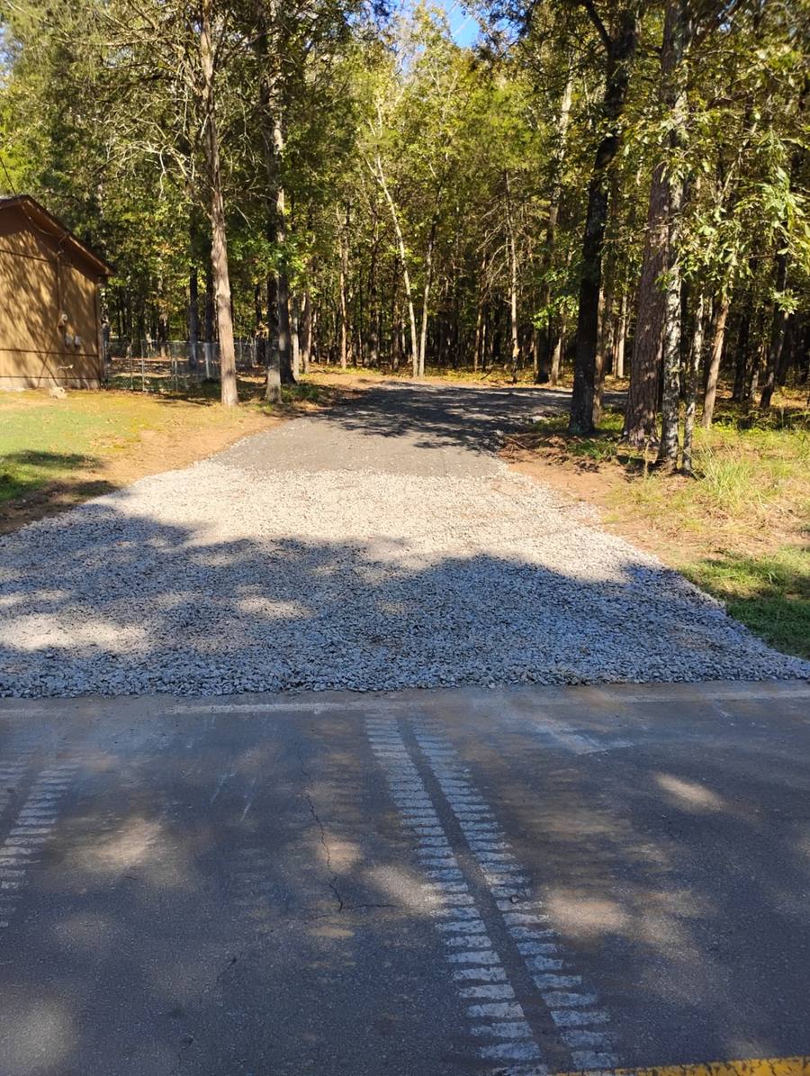 Fresh rock apron tying a wooded drive into the county road.