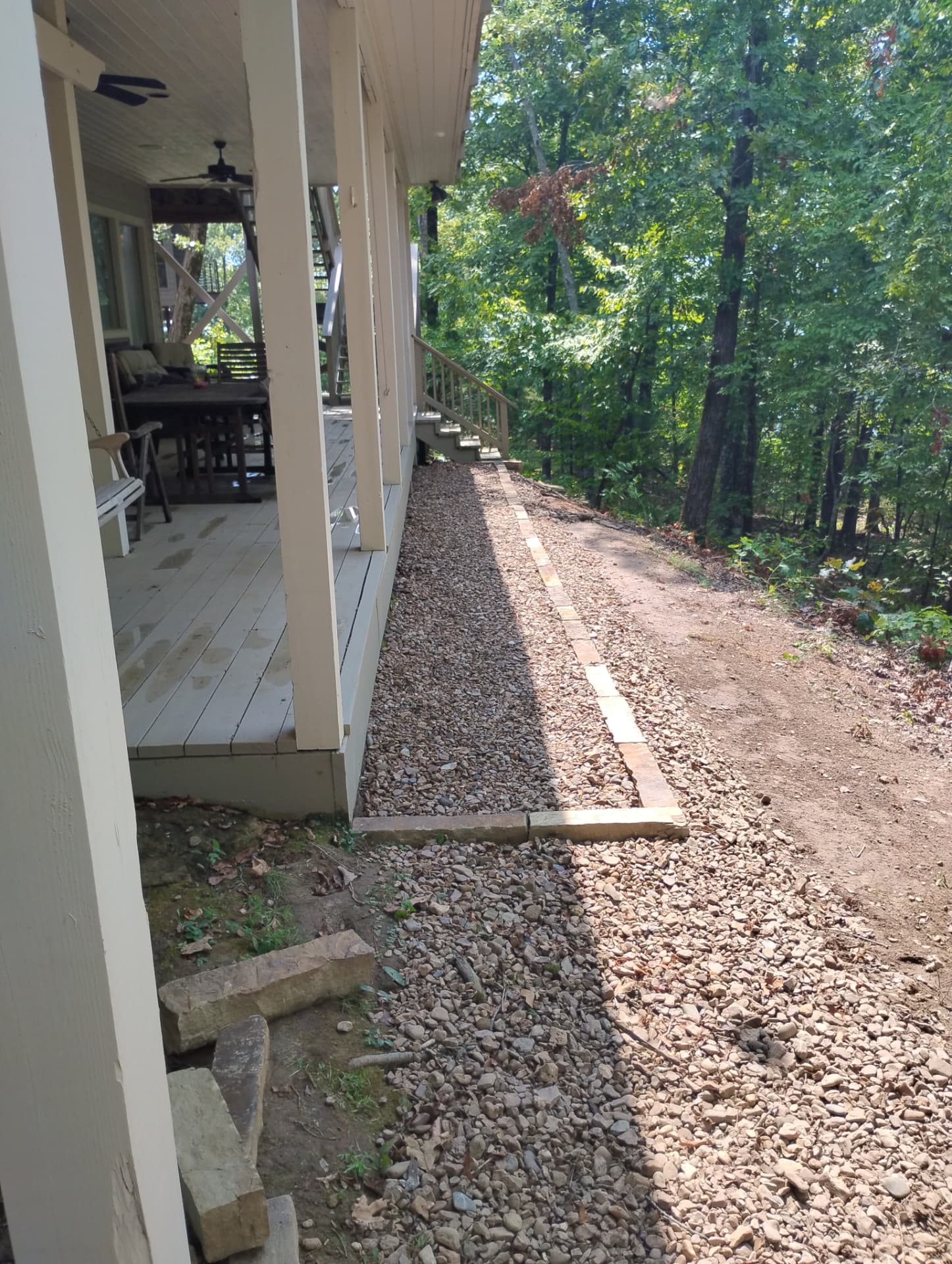 Finished gravel bed contained by a stone border along a wooden deck in Greers Ferry, Arkansas